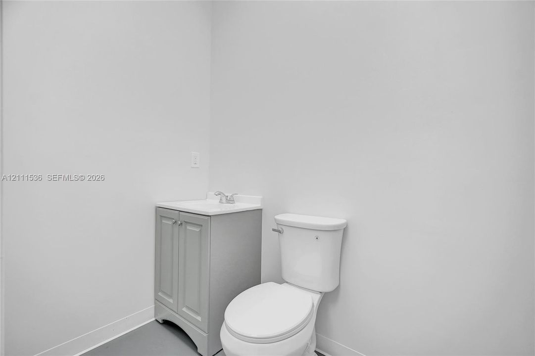 Vanity cabinet with neutral finish, integrated sink basin, dual-handle faucet, and standard-height toilet
