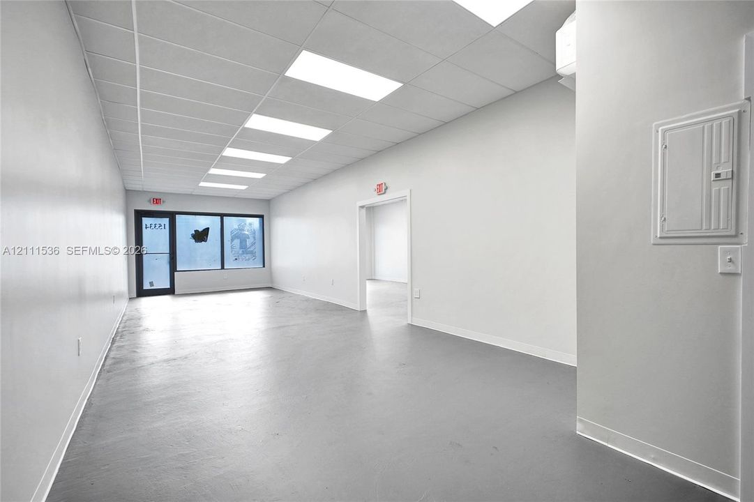Interior space featuring drop ceiling with recessed lighting, painted walls, solid-surface flooring, and glass-paneled entry door