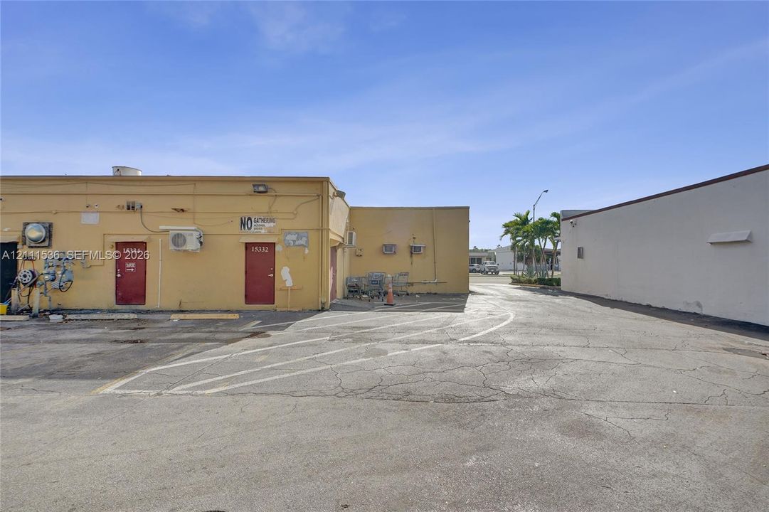 Commercial exterior featuring a concrete parking area and multiple building access points with painted metal doors