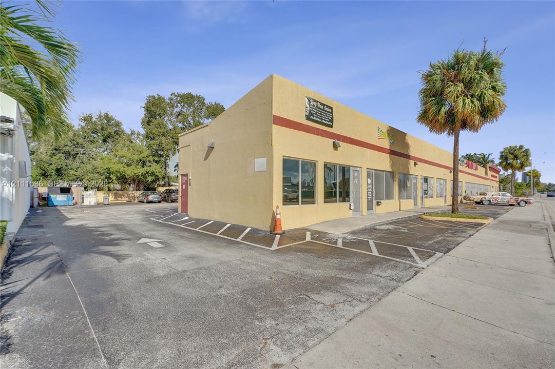 Commercial structure featuring a stucco exterior, multiple glass-pane storefront windows, a dedicated asphalt parking area, and painted parking stall markings