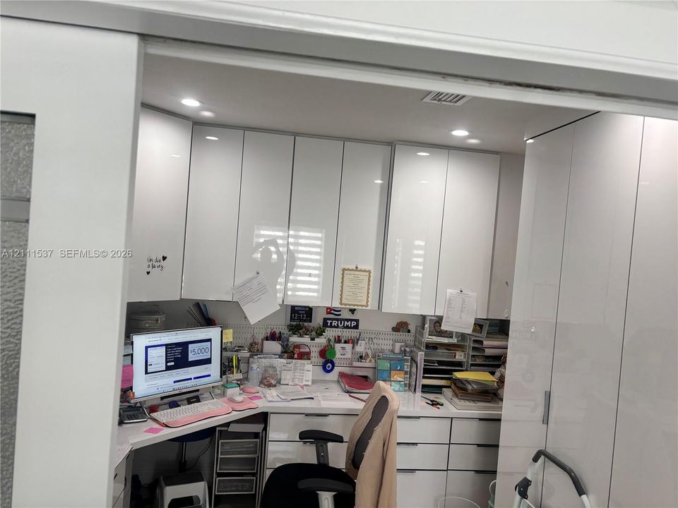 Custom built-in cabinetry with high-gloss white finish, recessed ceiling lighting, and integrated desk workspace