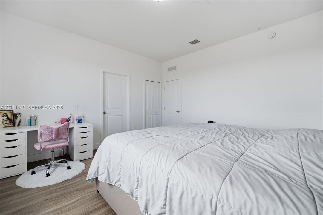 Neutral-toned interior featuring wood-finish flooring, crisp white walls, and multiple solid-core panel doors