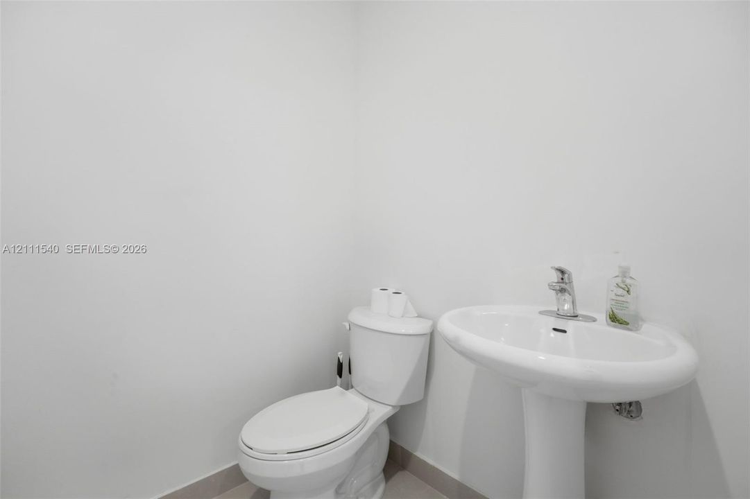White pedestal sink with a polished chrome faucet and matching white toilet