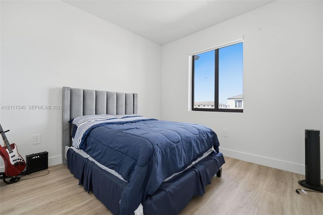 Neutral wall finish, wood-finish flooring, and a large window with black frame