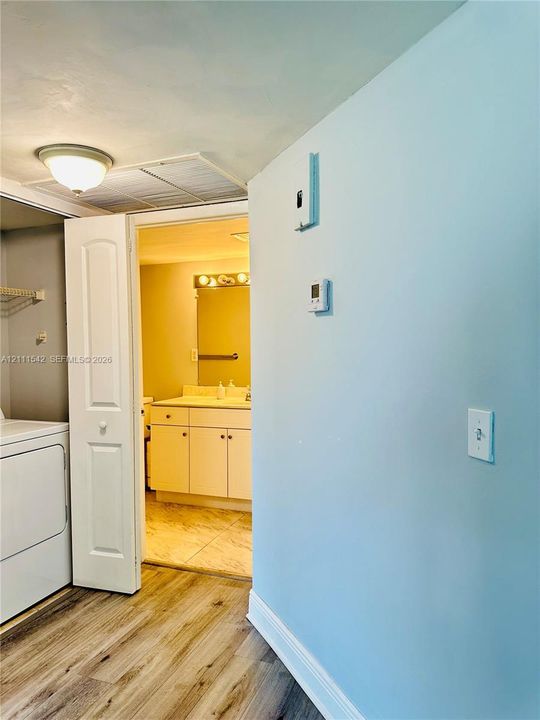 Wood-finish flooring, laundry area with bi-fold door, and vanity with multi-bulb light fixture