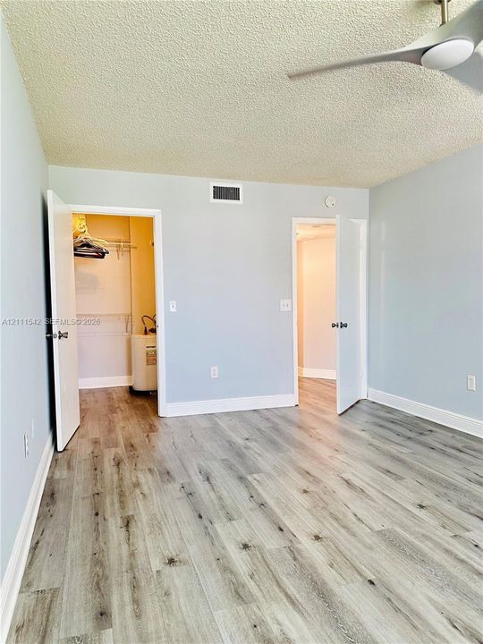 Interior space featuring wood-finish flooring, a neutral color palette, and a mounted multi-blade ceiling fan