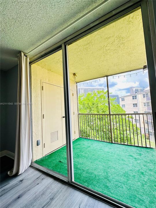 Private balcony featuring sliding glass doors, metal railing, and a storage closet