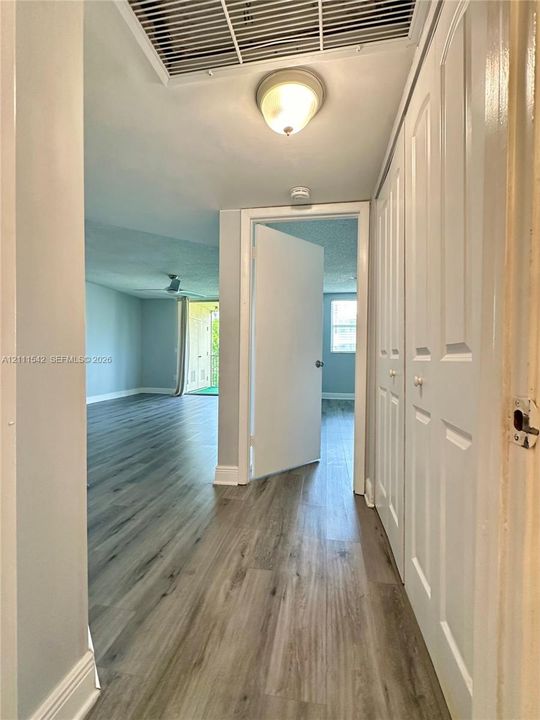 Hallway featuring wood-finish flooring, ceiling-mounted light fixture, and dual-panel closet doors
