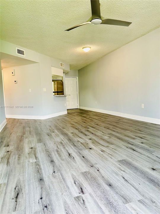 Interior space featuring wood-finish flooring, vaulted ceilings, a modern ceiling fan, and a pass-through opening to the kitchen area