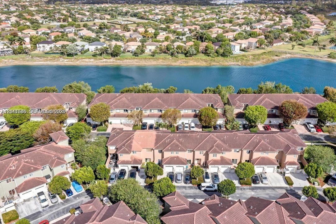 Aerial perspective of multi-family residences featuring tile roofing, stucco facades, attached garages, and proximity to a waterfront