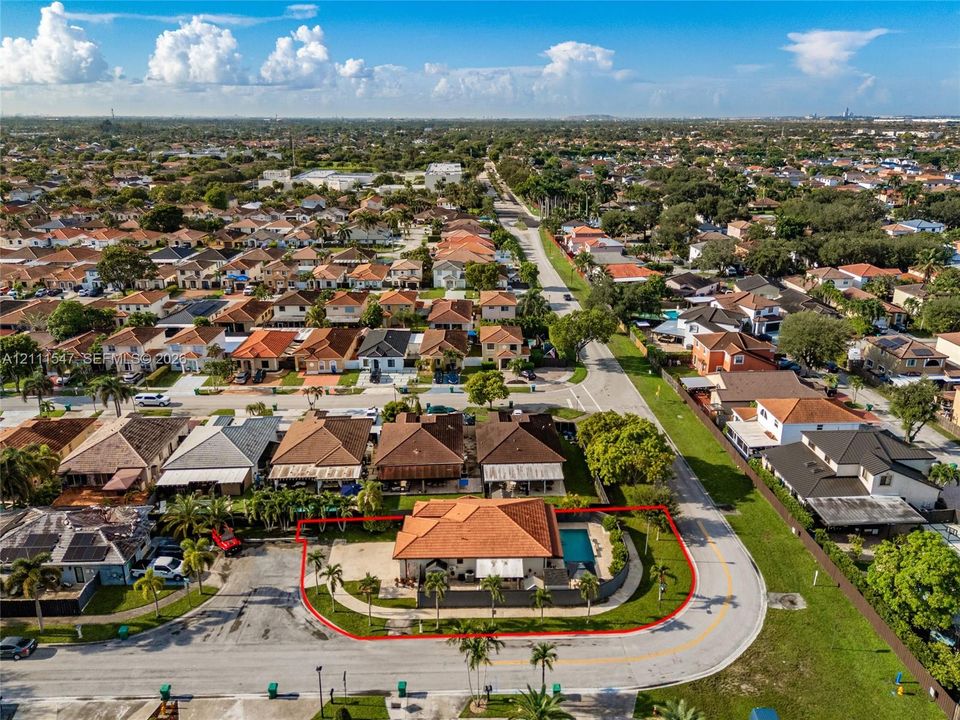 Corner lot property featuring a tile roof, an in-ground swimming pool, perimeter fencing, and mature palm trees