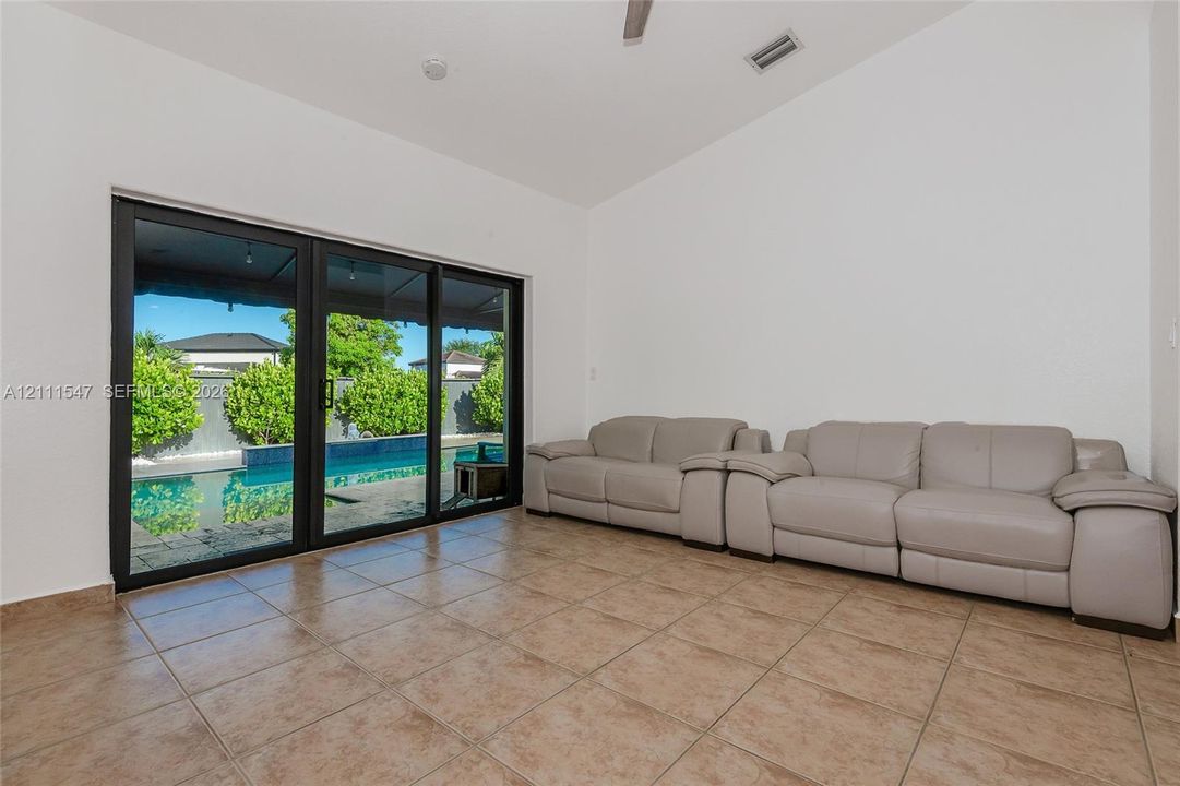 Sliding glass doors with dark frames, vaulted ceilings, ceramic tile flooring, and integrated ceiling fan