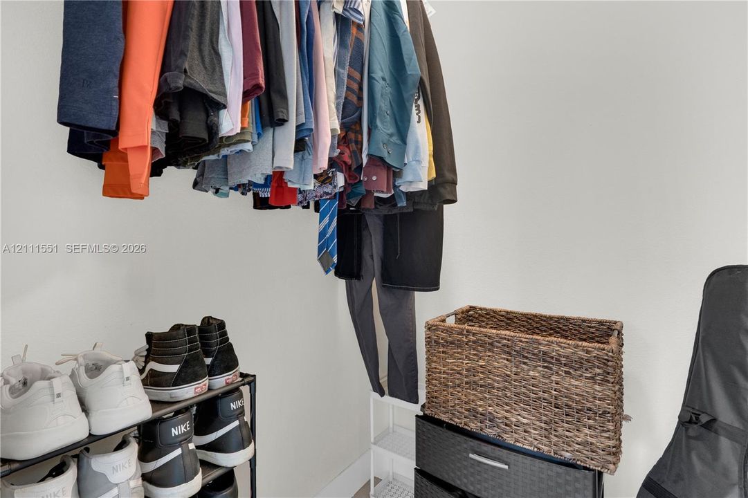 Storage space featuring a ceiling-mounted garment rod and neutral wall tones