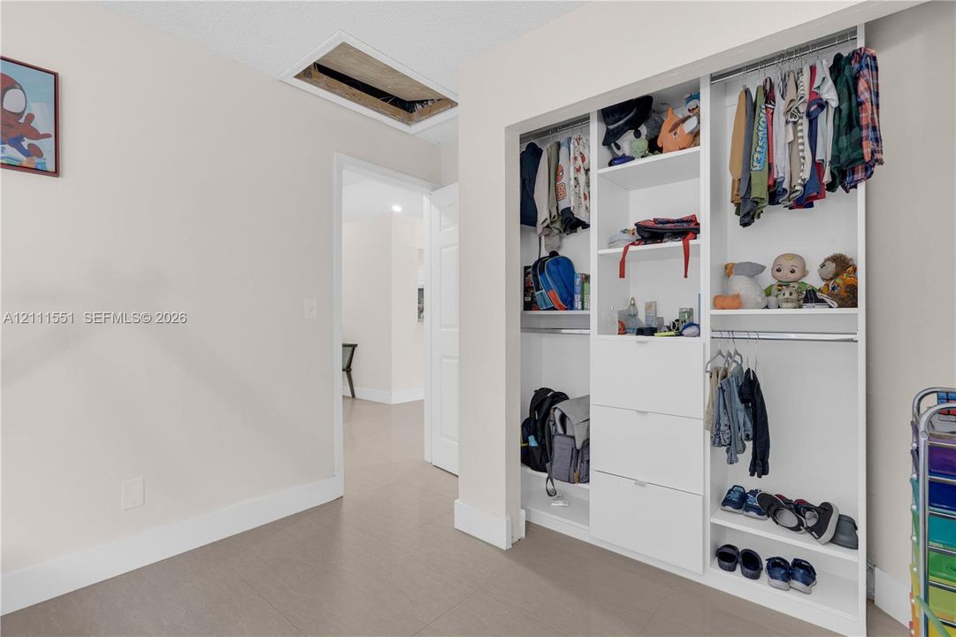 Built-in white organizational shelving unit featuring hanging rods, open display cubbies, and integrated pull-out drawers