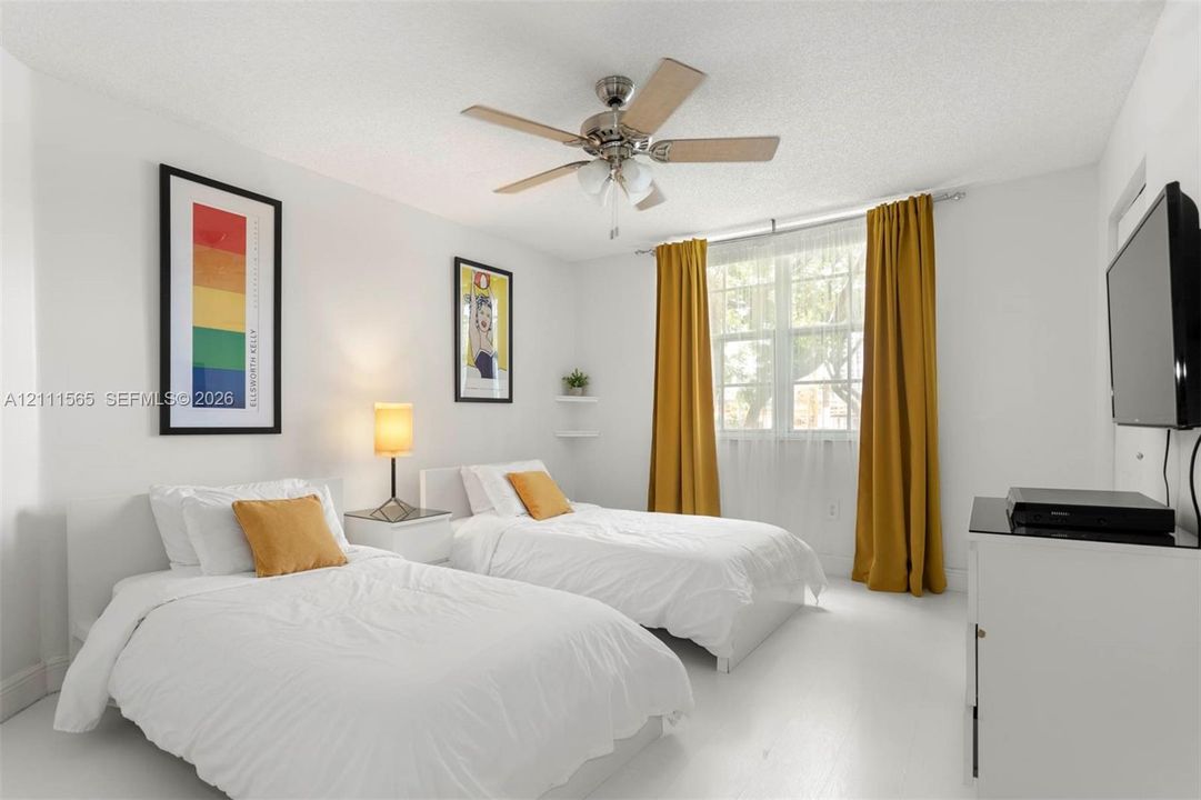 Multi-pane window with floor-to-ceiling drapery, brushed nickel ceiling fan with integrated lighting, and floating wall-mounted shelving