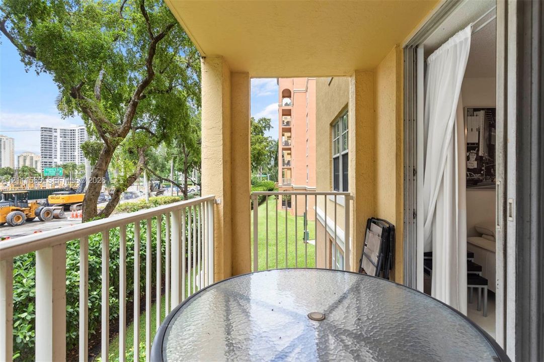 Covered balcony featuring white metal railings, stucco exterior walls, and sliding glass door access