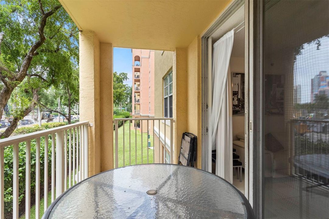 Covered balcony featuring white metal railings and sliding glass door access