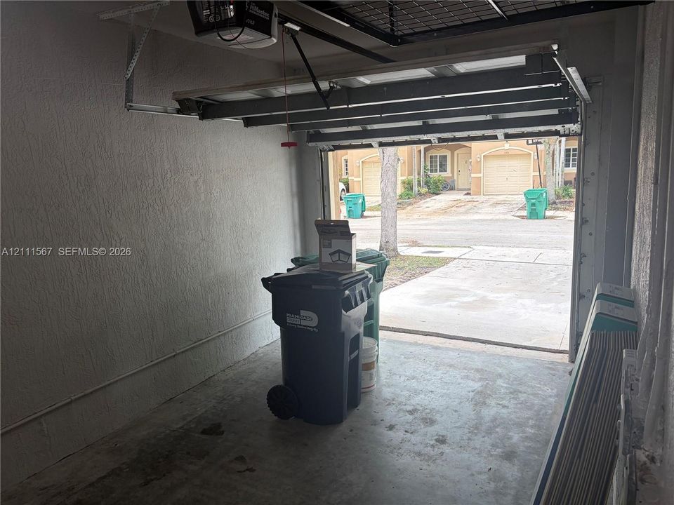 Enclosed garage featuring a concrete floor, textured walls, and an overhead automatic door opener