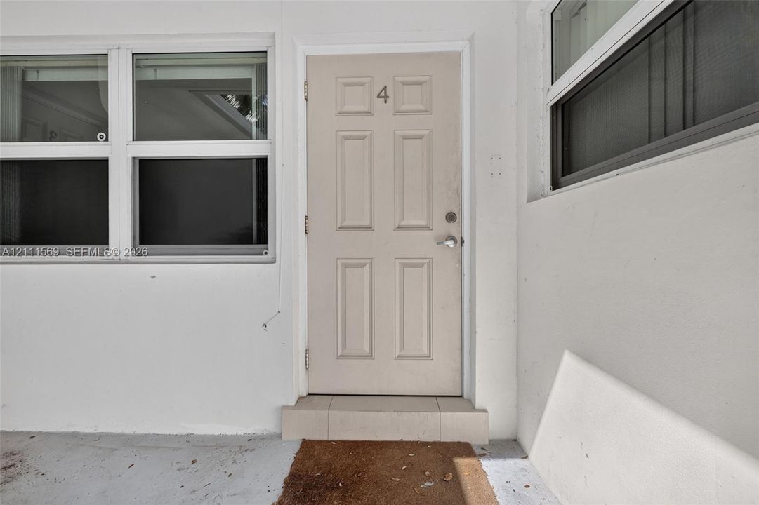 Entry featuring a neutral-toned, six-panel door with metallic hardware, accented by large multi-pane windows and a tiered exterior threshold