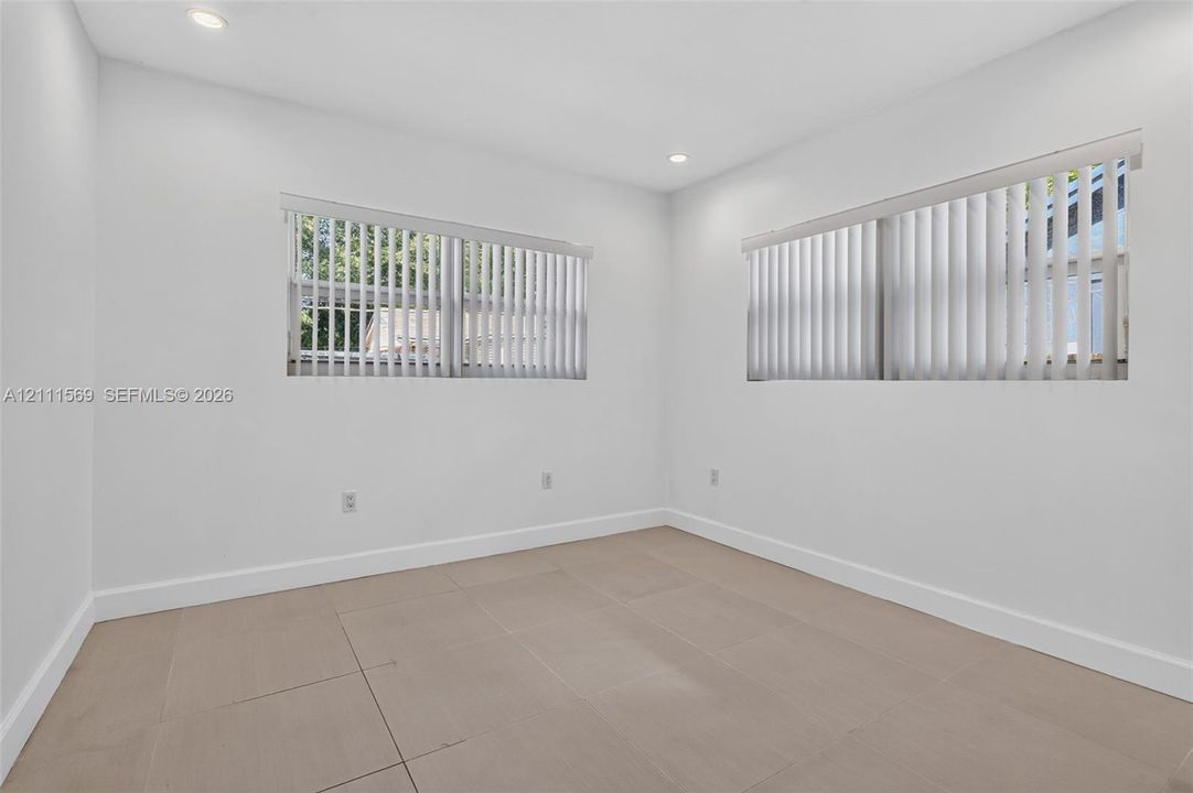 Neutral-toned tile flooring, recessed ceiling lighting, and windows featuring vertical blinds