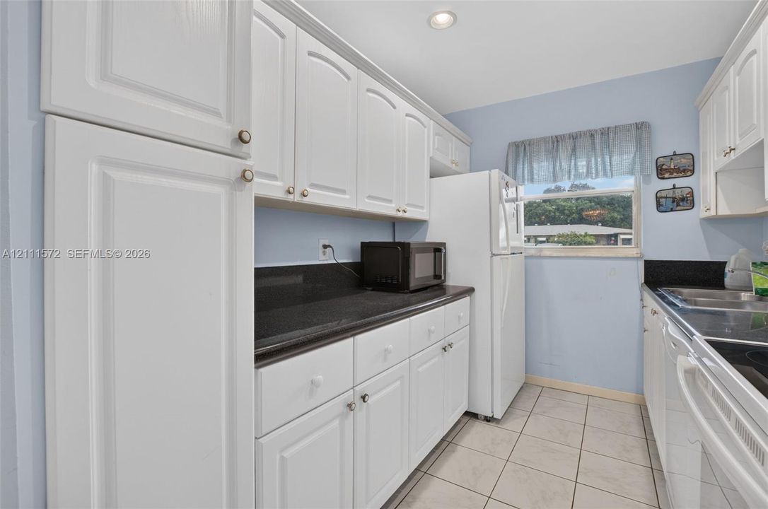 Kitchen featuring white cabinetry, stone-looking surface countertops tile flooring, and recessed lighting