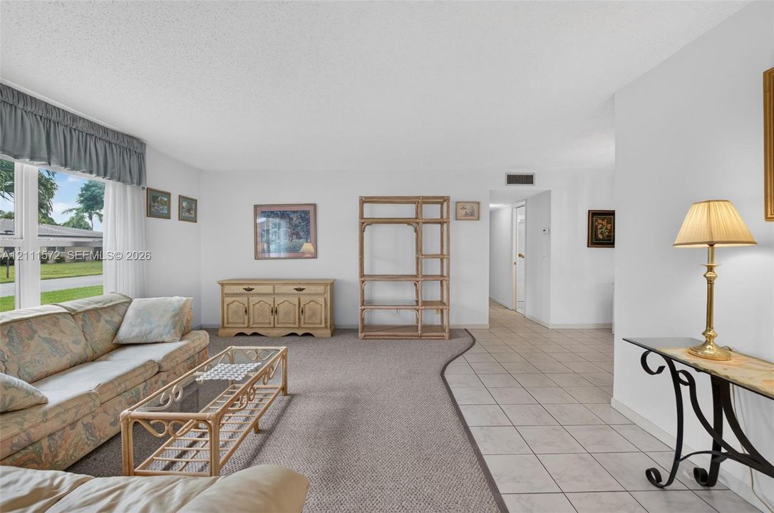 Living area featuring expansive impact windows, neutral berber carpeting, and ceramic tile flooring