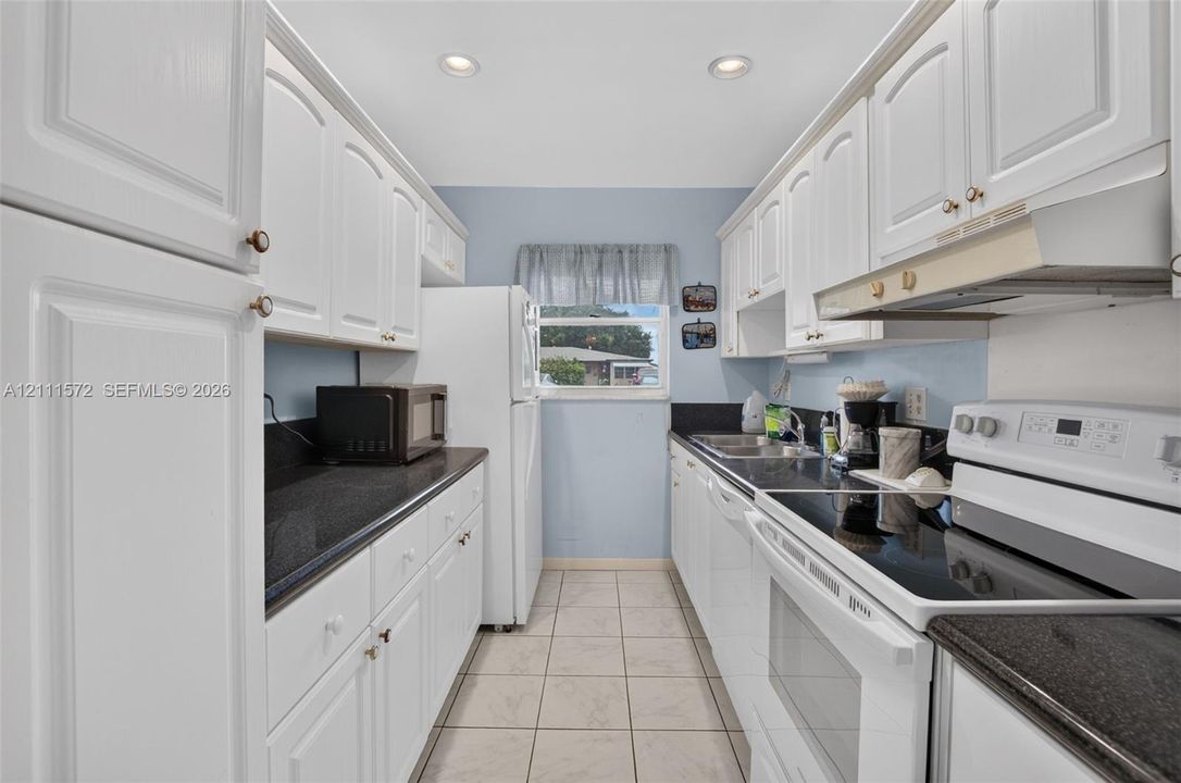 Kitchen featuring white cabinetry, stone-looking finish countertops, tile flooring, and recessed ceiling lighting