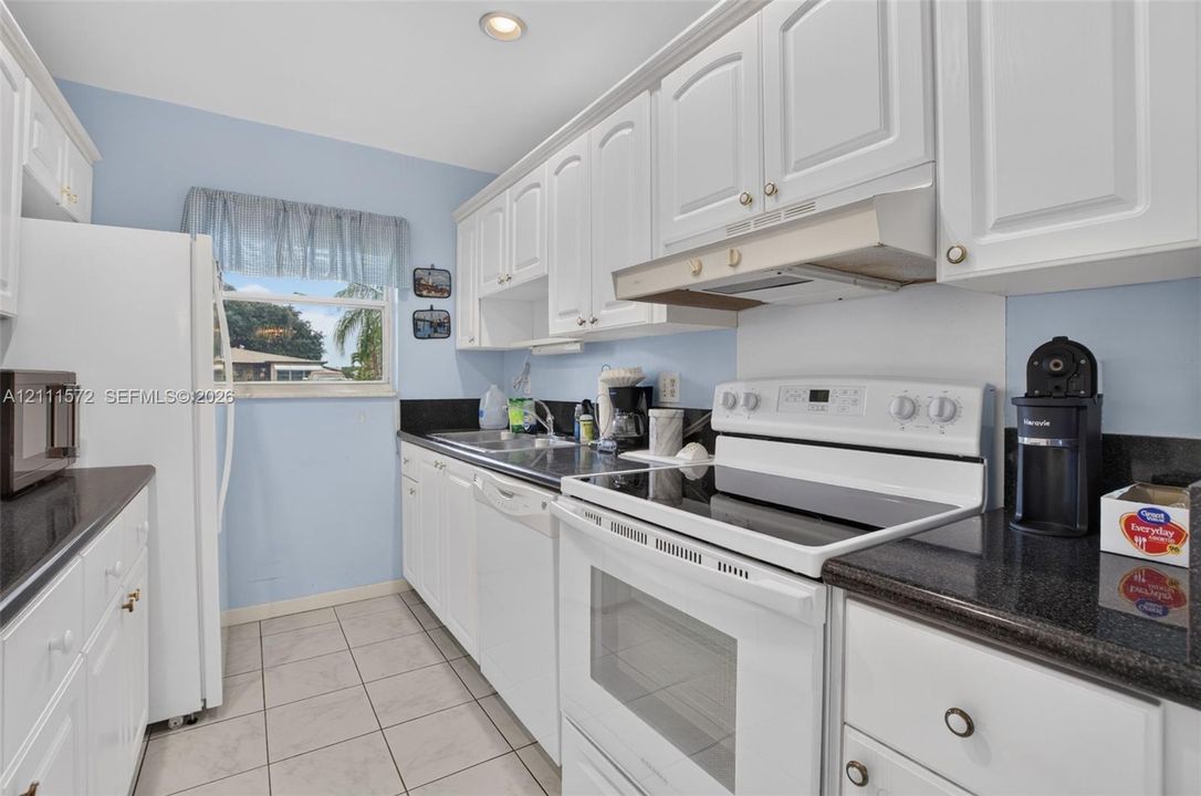 Kitchen featuring white cabinetry, stone-looking countertops, and recessed lighting