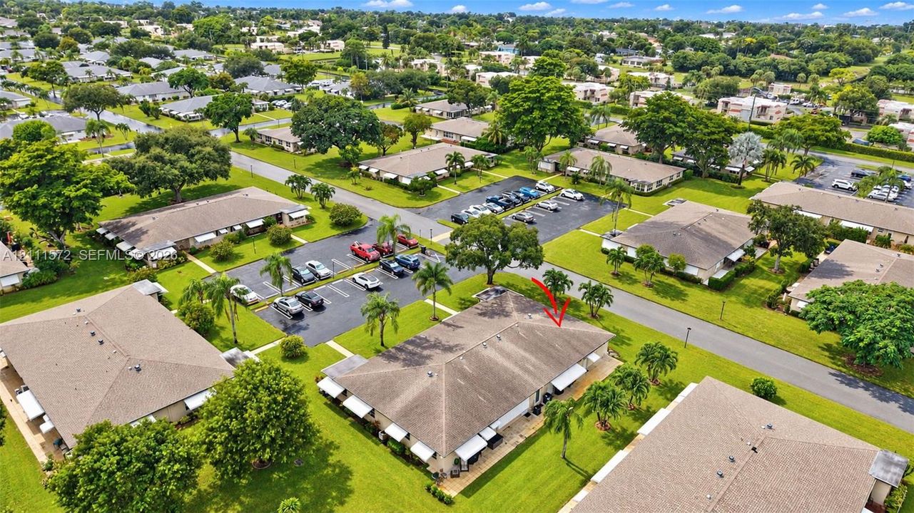 Aerial perspective of a single-story residence featuring a shingled roof, attached exterior awnings, and manicured surrounding lawn area
