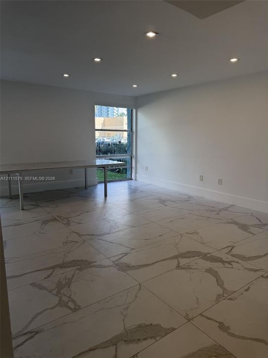 Large-format veined tile flooring, recessed ceiling lighting, and a tall picture window