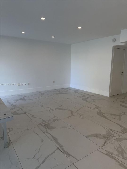 Neutral-toned large-format tile flooring with marble-pattern veining, complemented by recessed ceiling lighting