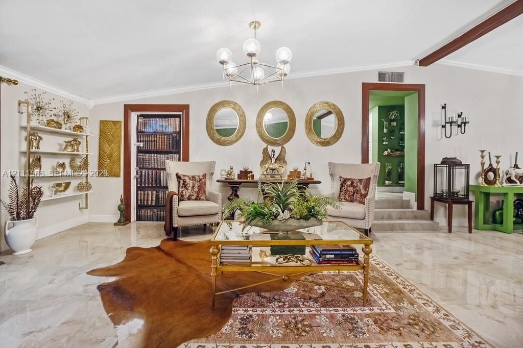 Polished stone flooring, architectural wall-mounted shelving unit, contemporary multi-globe chandelier, and raised-level entryway with dark wood trim