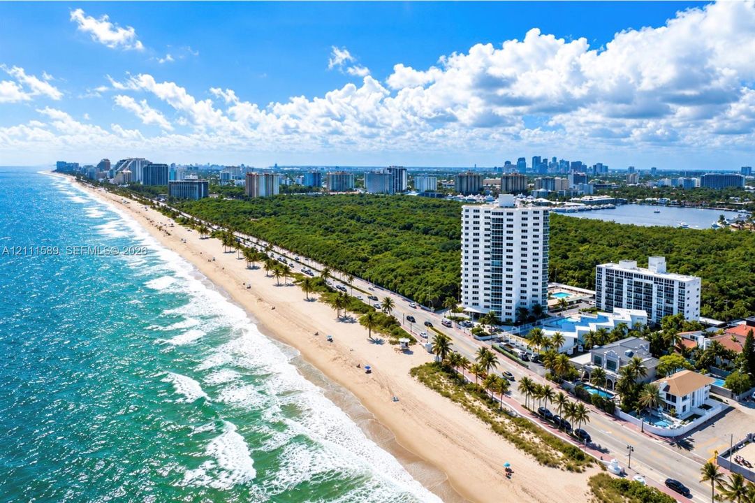 Aerial perspective featuring direct oceanfront access, sandy beach coastline, and coastal high-rise structures