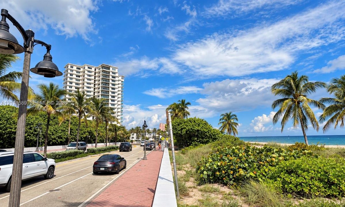 Coastal location featuring brick-paved sidewalks, dark-finish metal street lamps, and tropical landscaping along the shoreline