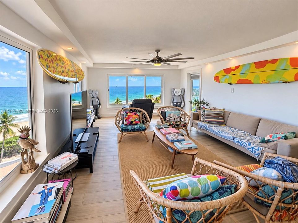 Living area featuring large-format windows, wood-finish flooring, and recessed ceiling lighting, showcasing an ocean horizon backdrop