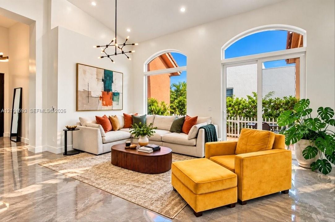 Vaulted ceilings, expansive arched windows, polished tile flooring, and a multi-arm modern pendant light fixture