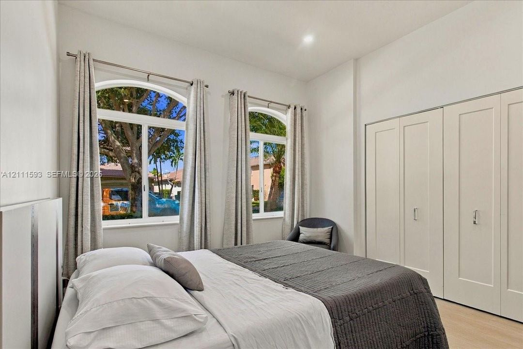 Room featuring dual arched windows, recessed lighting, and wall-to-wall built-in cabinetry with shaker-style doors