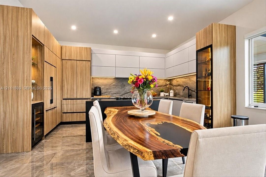 Modern kitchen featuring wood-finish cabinetry, matte black hardware, stone-finish backsplash, built-in wine storage, and recessed lighting
