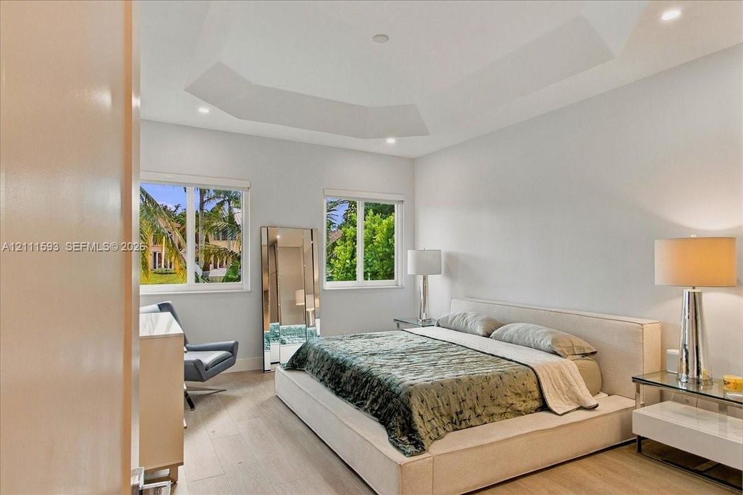 Tray ceiling with recessed lighting and light-toned wood-finish flooring