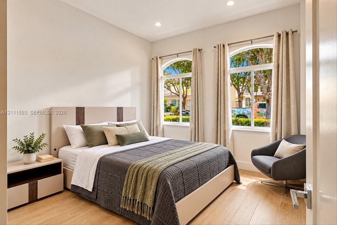Room featuring light wood-finish flooring, recessed lighting, and two arched windows