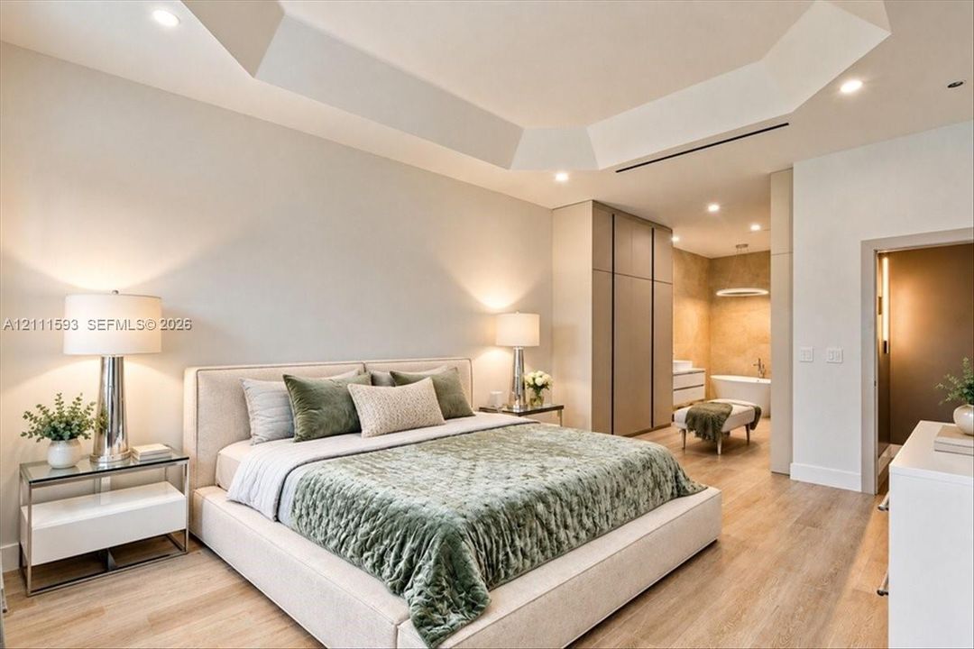 Tray ceiling with recessed lighting, integrated floor-to-ceiling cabinetry, wood-finish flooring, and neutral wall tones