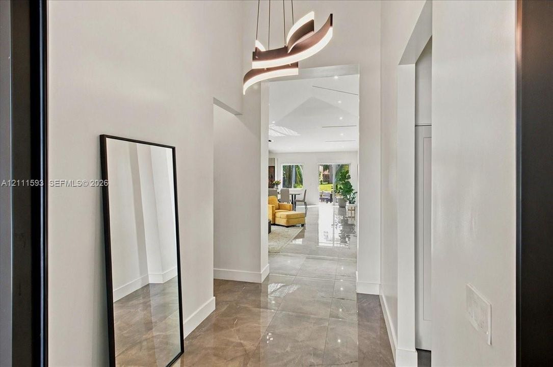 Foyer featuring high ceilings, large-format tile flooring, and a contemporary multi-tier sculptural chandelier