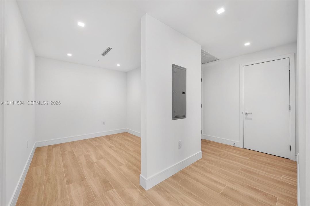 Interior room featuring wood-finish tile flooring, recessed ceiling lighting, and a central partition wall with an integrated electrical service panel