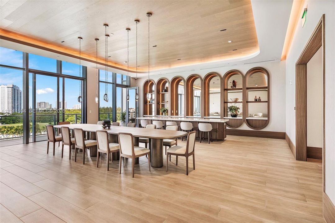 Wood-finish flooring, coved ceiling with recessed lighting, floor-to-ceiling glass paneling, and custom built-in arched cabinetry featuring stone countertops