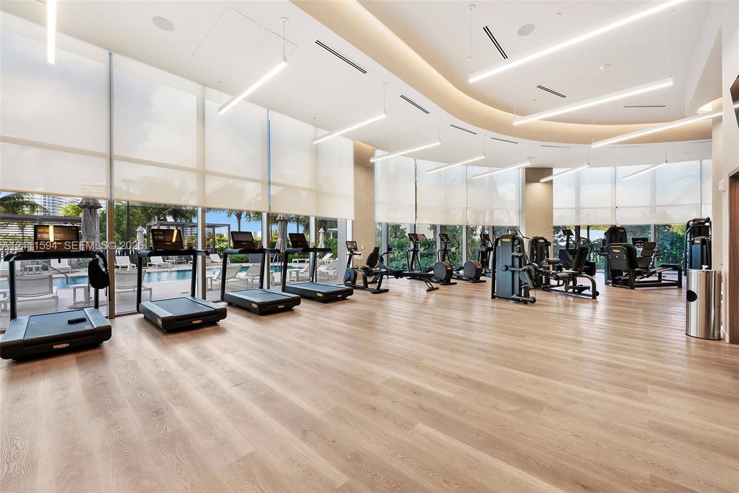 Fitness center featuring floor-to-ceiling windows, wood-finish flooring, recessed lighting, and linear suspended light fixtures