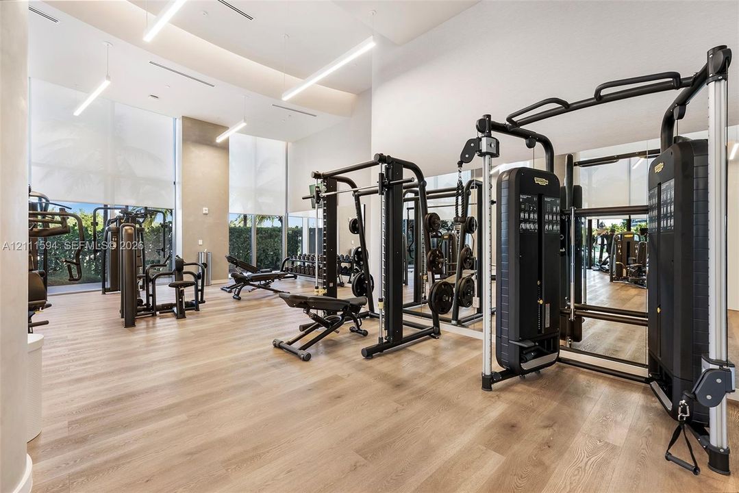 Fitness center featuring wood-finish flooring, floor-to-ceiling windows, and recessed lighting