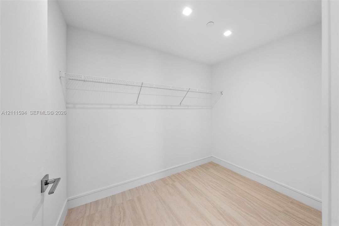 Walk-in closet featuring light wood-finish flooring, white walls, recessed ceiling lighting, and white wire shelving