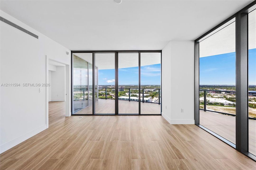 Floor-to-ceiling glass sliding doors, expansive wraparound terrace, wood-finish flooring, and minimalist white interior walls