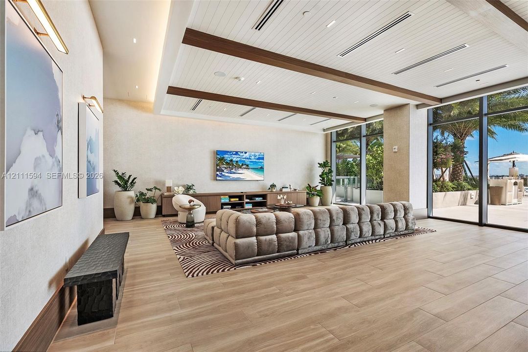 Expansive room featuring a wood-plank ceiling with decorative beams, floor-to-ceiling glass windows, recessed lighting, and large-format wood-finish flooring