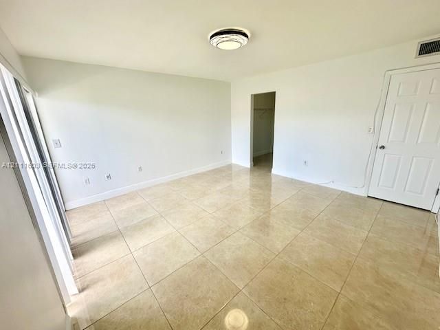 Neutral-toned tile flooring, flush-mount circular ceiling lighting, and a six-panel interior door